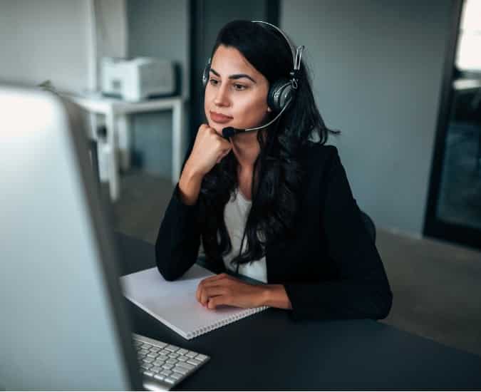 Outbound Call Center Agent Looking at Her Computer Screen While Wearing a Headset